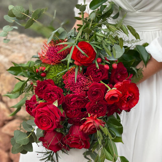 Detalle de ramo de novia con rosas rojas, ranúnculos, leucospermum, hypericum y eucalipto