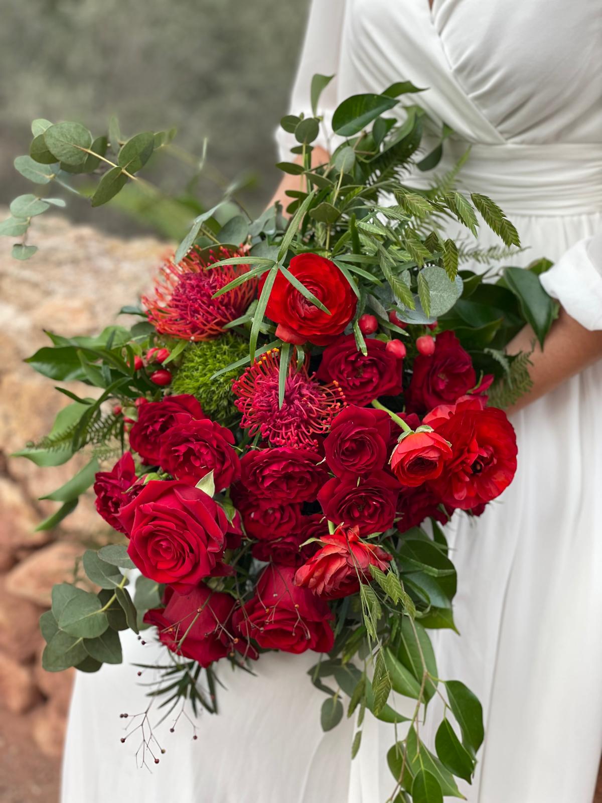 Detalle de ramo de novia con rosas rojas, ranúnculos, leucospermum, hypericum y eucalipto