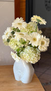 Ramo de gerberas blancas con hortensias y crisantemos verdes en jarrón de cerámica blanca con relieve de flor