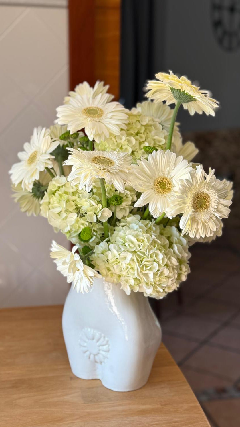 Ramo de gerberas blancas con hortensias y crisantemos verdes en jarrón de cerámica blanca con relieve de flor