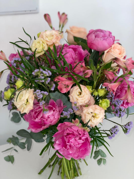 Ramo de peonías fucsia con lisianthus crema, rosas melocotón, alstroemerias rosas y limonium lila