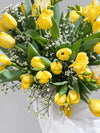 Detalle de ramo de tulipanes y fresias amarillas con limonium blanco y papel de seda blanco