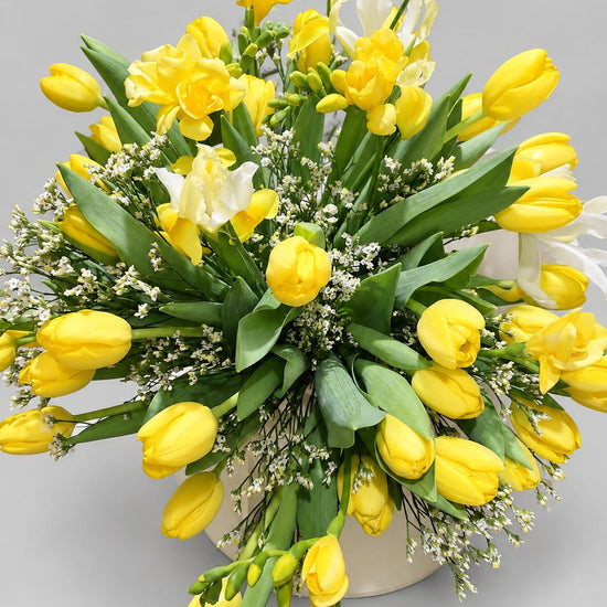 Ramo de tulipanes y fresias amarillas con limonium blanco en jarrón de cerámica