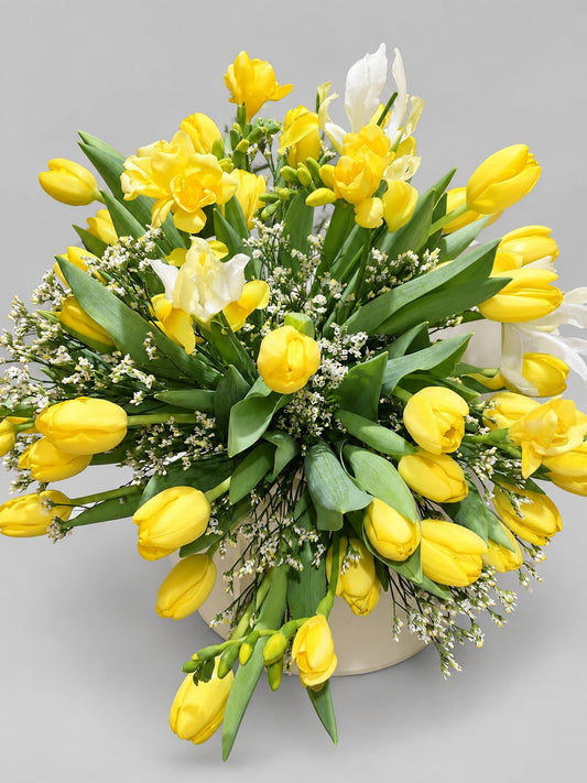 Ramo de tulipanes y fresias amarillas con limonium blanco en jarrón de cerámica