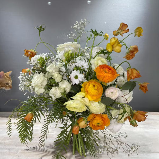 Ramo de flores blancas y naranjas con un gato asomando a la izquierda