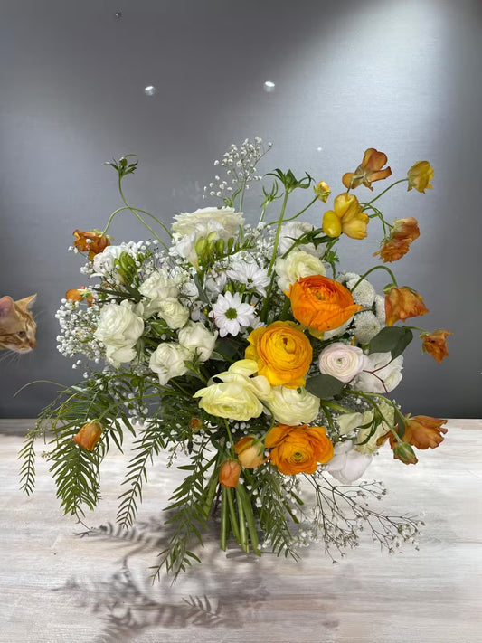 Ramo de flores blancas y naranjas con un gato asomando a la izquierda
