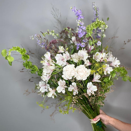 Wild Poetry — ramo silvestre con delphinium lila y flores blancas