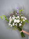 Wild Poetry — ramo silvestre con delphinium lila y flores blancas
